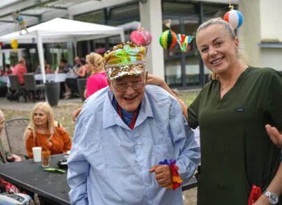 Mitarbeiterin mit lachendem Bewohner mit goldener Kappe
